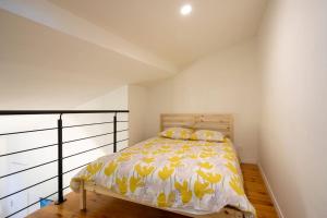 a bedroom with a bed with yellow and white sheets at Studio mezzanine "chaumiane" proche de la gare in Issoire