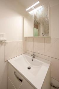 a white bathroom with a sink and a mirror at Studio mezzanine "chaumiane" proche de la gare in Issoire +4 photos