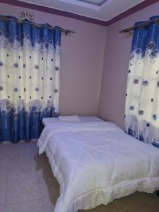 a bedroom with a bed with blue and white curtains at Christa's Haven in Siaya