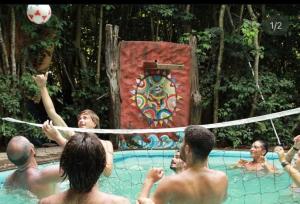 a group of men playing volleyball in a pool at Lagarto Na Banana Hostel in Pipa
