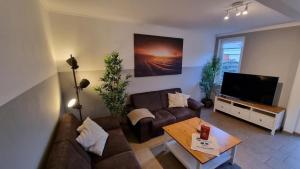 sala de estar con sofá y TV en Ferienhaus-Klippenbarsch, en Dornumersiel