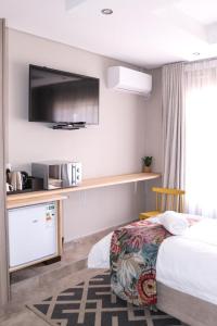 um quarto de hotel com uma cama e uma televisão de ecrã plano em EDEN BOUTIQUE HOTEL em Kokstad