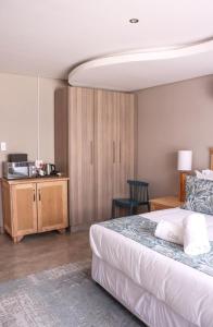 a bedroom with a bed and a desk with a television at EDEN BOUTIQUE HOTEL in Kokstad