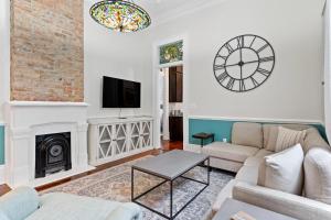 a living room with a couch and a clock on the wall at Bywater Bungalow in New Orleans