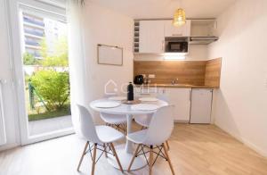 cocina y comedor con mesa blanca y sillas en Pascal’s Cosy Retreat, en Rosny-sous-Bois