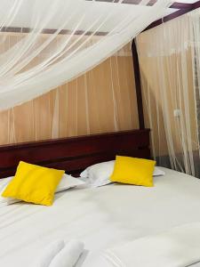 a bed with two yellow pillows on top of it at Gallene Gala Nature Resort in Kitulgala