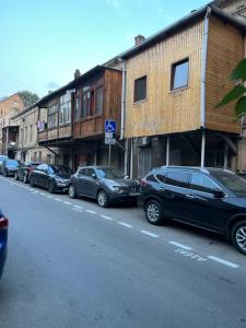Une rangée de voitures garées sur le côté d'une rue dans l'établissement ბინა, à Tbilissi