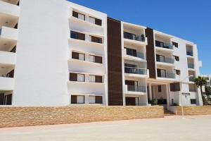 um grande edifício de apartamentos branco com uma cerca em frente em luxueux appartement touristique em Agadir