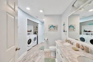 a bathroom with two sinks and a washer and dryer at Island Paradise 3 Bed Waterfront/Heated Pool in Clearwater Beach