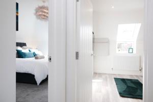 a white bedroom with a bed with blue pillows at Nightingale - Perfect location close to the Beach - Free Parking in Bournemouth