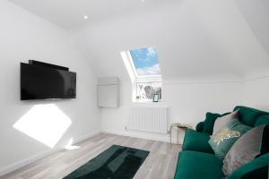 a living room with a green couch and a flat screen tv at Nightingale - Perfect location close to the Beach - Free Parking in Bournemouth