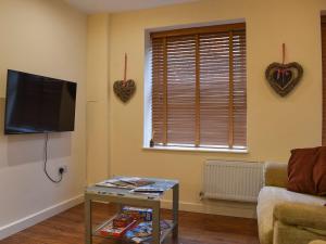 a living room with a tv and a table and a window at Walnuts Nest in Minehead