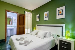 セビリアにあるアパートメント アラメダの緑の壁の白いベッドが備わるベッドルーム1室
