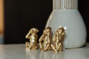 drei kleine goldene Figuren auf einem Tisch neben einer Vase in der Unterkunft Huis 7 in Ypern