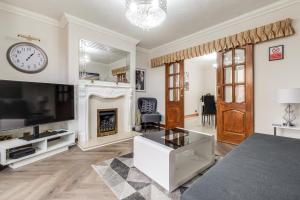a living room with a fireplace and a clock on the wall at Comfortable and Spacious Home - Free Parking in Bedford