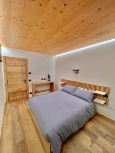 1 dormitorio con 1 cama grande y techo de madera en Le Stue en Pieve di Cadore