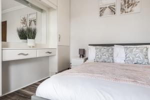 a white bedroom with a bed and a dresser at Comfortable and Spacious Home - Free Parking in Bedford