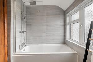 a white bath tub in a bathroom with a window at Comfortable and Spacious Home - Free Parking in Bedford