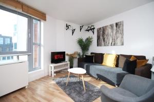 a living room with a couch and a tv at Stylish 2 Bed Flat in HEART of Cardiff City Centre in Cardiff