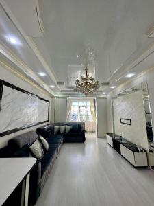 a living room with a couch and a chandelier at Двухкомнатная элитка Ала-Арча in Bishkek