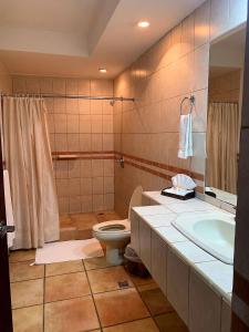 a bathroom with a toilet and a sink and a tub at Hotel Casa del Sol in Managua