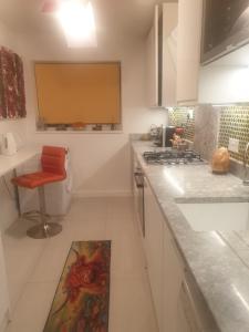 a white kitchen with a red chair and a sink at Beautiful Apartment in High Wycombe in Buckinghamshire