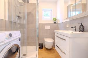 a bathroom with a washing machine and a sink at Premium Zuhause - Seeblick, Balkon, Pool & Seepromonade in Langscheid