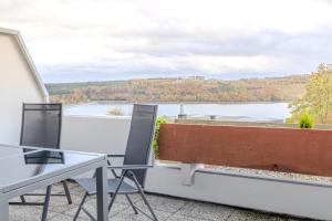 a balcony with a table and chairs and a view of a lake at Premium Zuhause - Seeblick, Balkon, Pool & Seepromonade in Langscheid