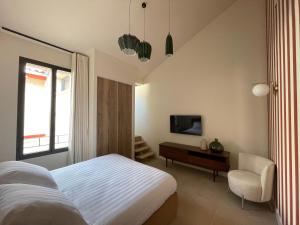 a bedroom with a bed and a tv and a chair at Villa Chiesa Maison Hôtelière in Le Grau-du-Roi