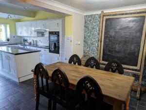 een keuken met een tafel en stoelen en een schoolbord bij Spacious Country Cottage with 3 Double Bedrooms in East Dereham