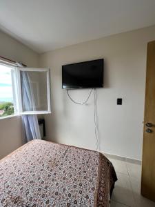 um quarto com uma cama e uma televisão de ecrã plano na parede em Sexto al mar em Santa Teresita