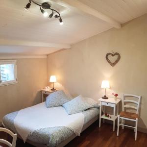 1 dormitorio con 1 cama, 2 mesas y un corazón en la pared en Au Petit Nid de Sanguinet, en Sanguinet