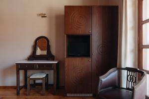 a room with a desk and a television and a cabinet at Chrysiida Apartments Kalavrita in Kalavrita