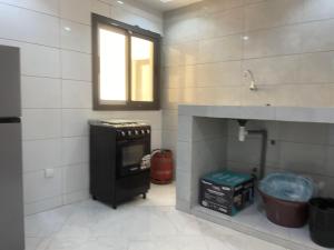 cocina pequeña con fogones y ventana en Résidence Cheikh Mahy Cisse Appartements, studios et chambres a louer meublé et climatisé, en Kaolack