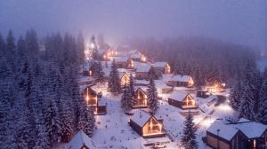 een dorp bedekt met sneeuw 's nachts met lichten bij SKOGUR - Home & Resort in Boekovel