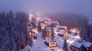 a village covered in snow at night with lights at SKOGUR - Home & Resort in Bukovel