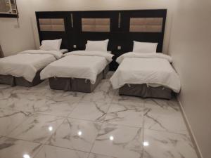 three beds in a room with a marble floor at كازا رست للوحدات السكنية in Ḩayy aş Şāliḩīyah