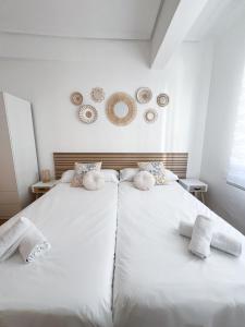 two beds in a bedroom with white sheets and towels at El Balcón de Miguel in Logroño