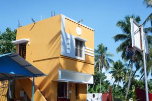 a yellow building with a window and palm trees at Prism Holiday Resort PONDICHERRY Kalapet in Kālapettai