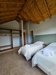 two beds in a room with wooden ceilings at Comarca Fueguina in Ushuaia
