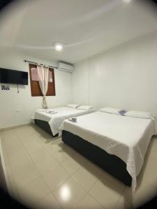 Pokój z dwoma łóżkami i telewizorem w obiekcie Hostal Casa W w mieście Cartagena de Indias