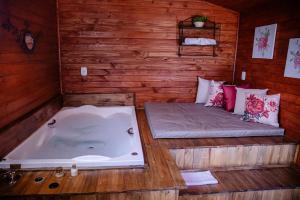 a sauna with a tub and a bed in it at Refúgio do Caracol Pipas e Chalés in Canela