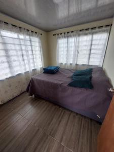 a bedroom with a bed and two windows at GLAMPING EL Mirador in Ibagué