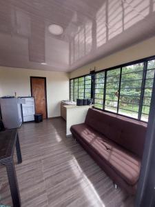 una sala de estar con sofá en una habitación con ventanas en GLAMPING EL Mirador en Ibagué