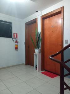 a hallway with a wooden door and a potted plant at Aptos Farroupilha in Farroupilha