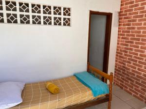 małe łóżko w pokoju z ceglaną ścianą w obiekcie Itajaí Hostel Pousada w mieście Itajaí
