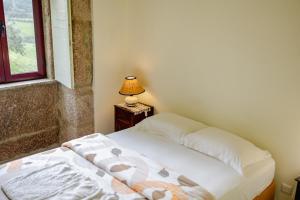 a bedroom with a bed and a table with a lamp at Quinta da Cerdeira in Seia