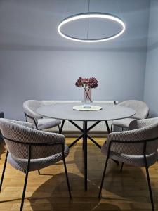 een tafel met stoelen en een vaas met bloemen erop bij Goreta032 Luxury Apartment 2 in Vukovar