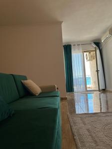 uma sala de estar com um sofá verde e uma janela em Beach front Superior Apartment em Durrës
