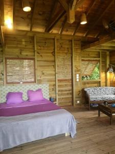 een slaapkamer met een paars bed in een houten kamer bij cabane entre les arbres in Deshaies